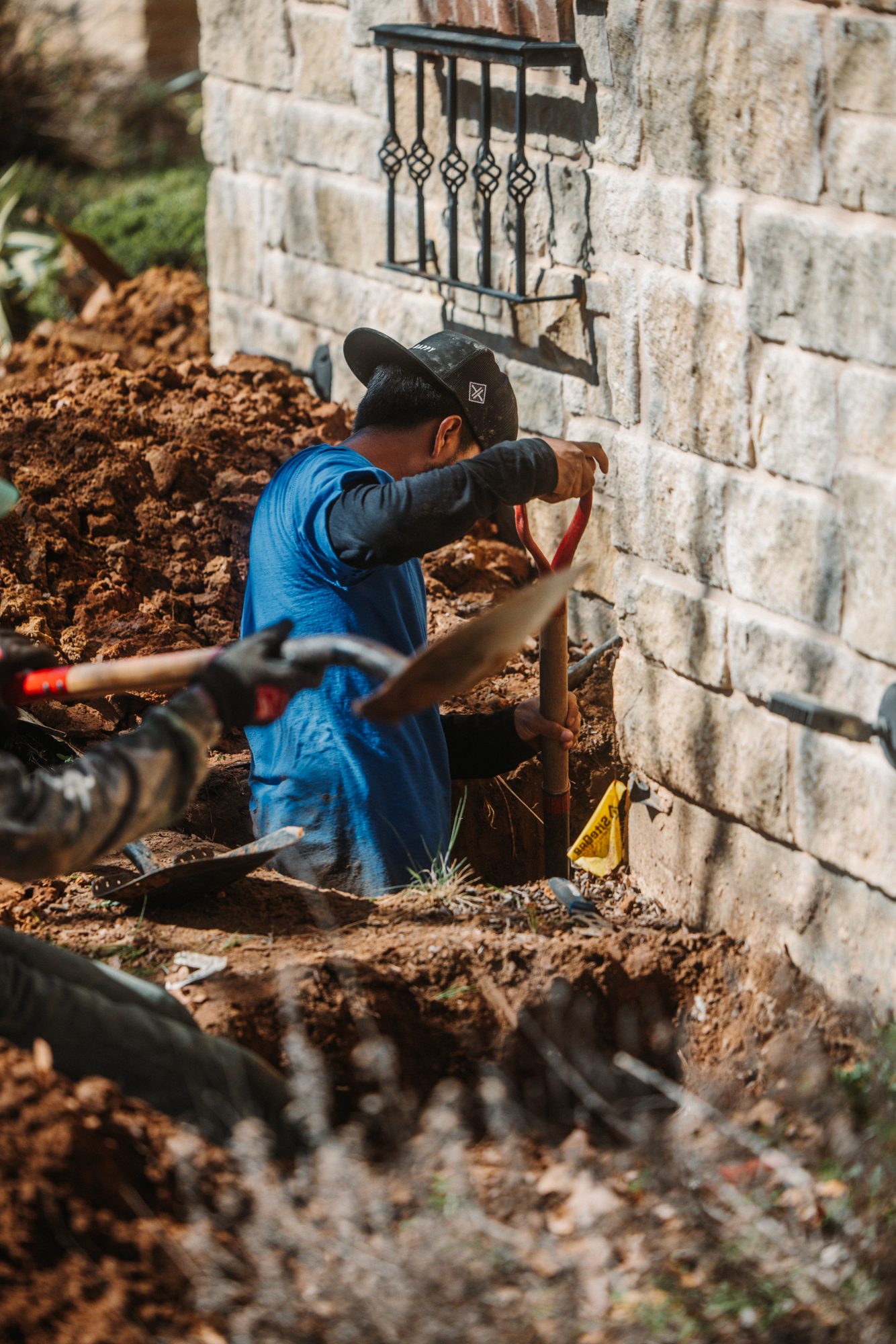 Crew digging stone house, Imperial Foundation Repair job site in North Texas